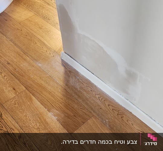 קיר עם תיקוני צבע על רצפת עץ